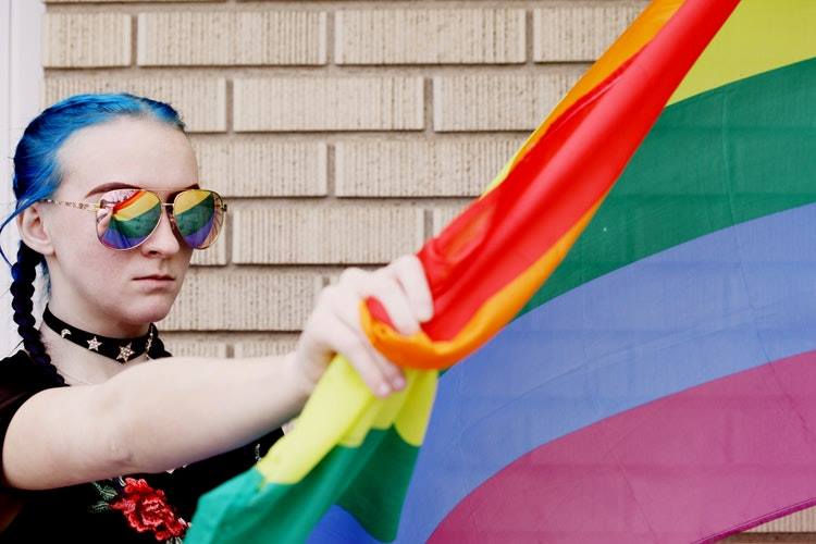 young blue-haired girl with rainbow flag